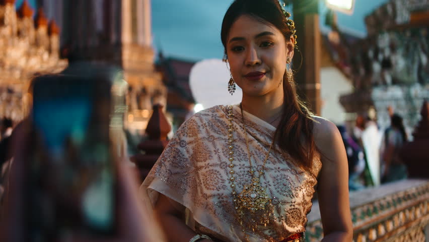 Thai woman in traditional dress posing for a photo at wat arun