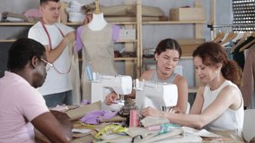 Positive interested female fashion design students stitching on machines and friendly talking, sharing sewing tips in hands-on workshop while male classmate adjusting garment on mannequin - Powered by Shutterstock - Get 15% off with code: PIKWIZARD15