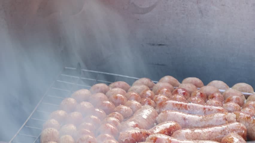 Hand cuts and grills sausages over smoky charcoal at traditional open-air street market stall