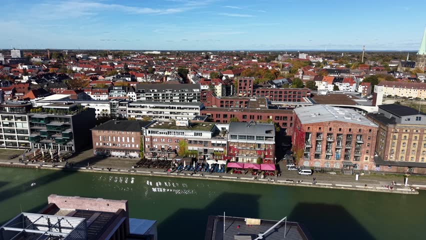 Luxury waterside promenade riverwalk in German town with noble apartments on sunny day. Aerial lateral wide shot. Historic town of Münster, Germany.