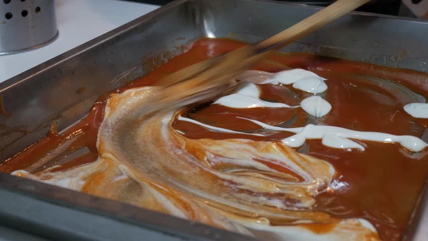 Layering creamy sauce in lasagna tray for comforting homemade meal
