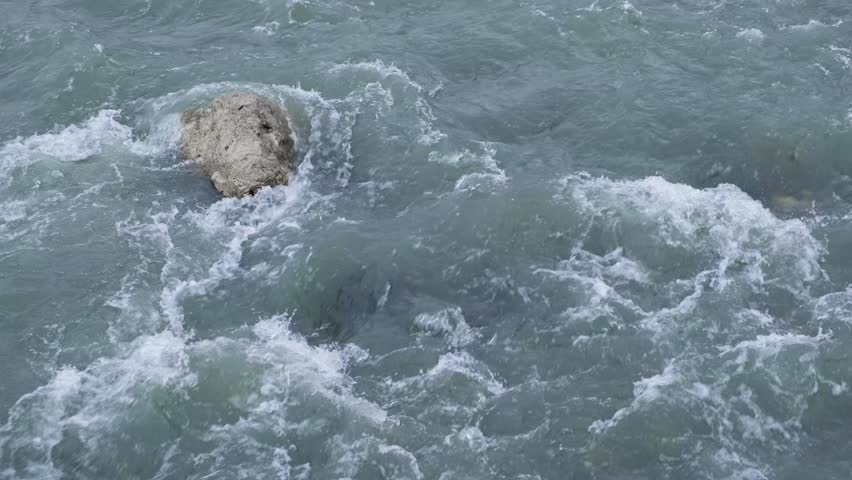 rapid water flow in mountain river with stone, close-up, slow motion
