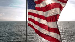 American flag in coastal wind. US flag over open water. Flag rippling in ocean air. American flag above water. - Powered by Shutterstock - Get 15% off with code: PIKWIZARD15