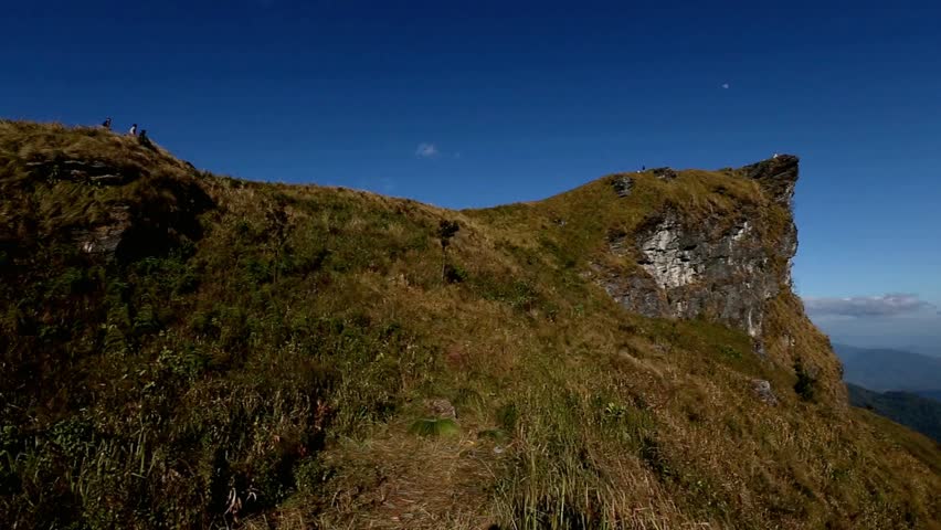 Hiking trail leading to a rocky mountain peak under a clear blue sky in daylight