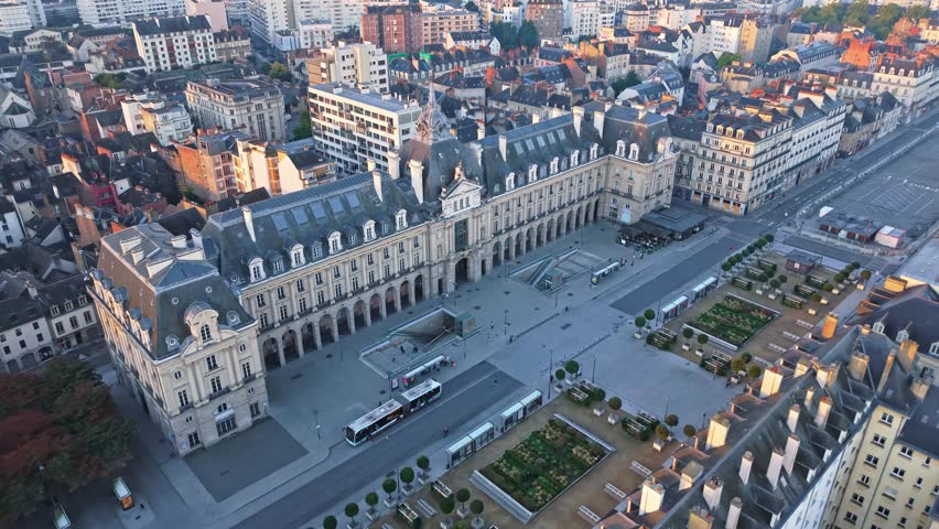Place de la Republique, square and Palais du Commerce in Rennes, France at sunrise, golden light on historic architecture. Aerial drone forward descending
