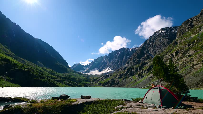 a man on the shore of Lake Kuyguk in the Altai Mountains at a campsite