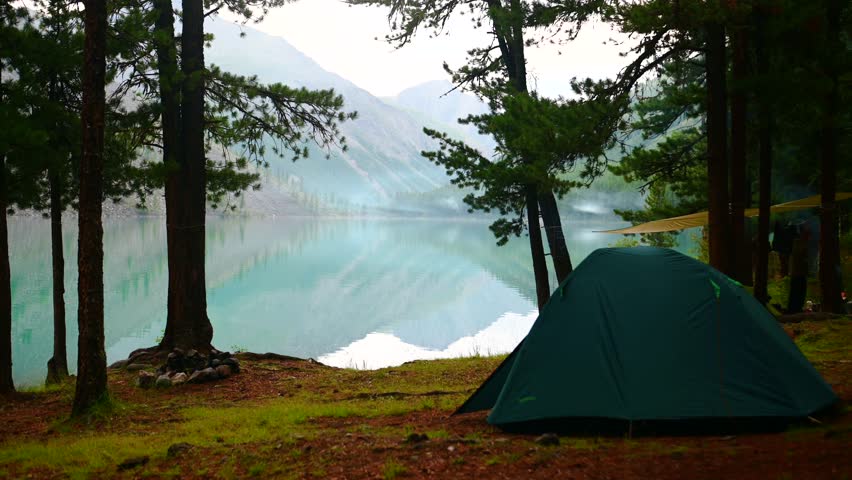a man on the shore of Lake Kuyguk in the Altai Mountains at a campsite
