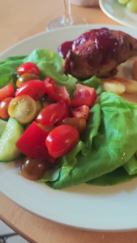 A plate with fresh salad, roasted vegetables, and glazed meat creates a colorful dinner scene. The moment highlights healthy eating, home cooking, and vibrant, wholesome meals.