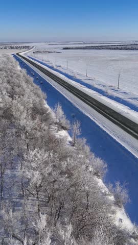 trucks and cars are driving on the highway in winter, and the trees are covered in white frost