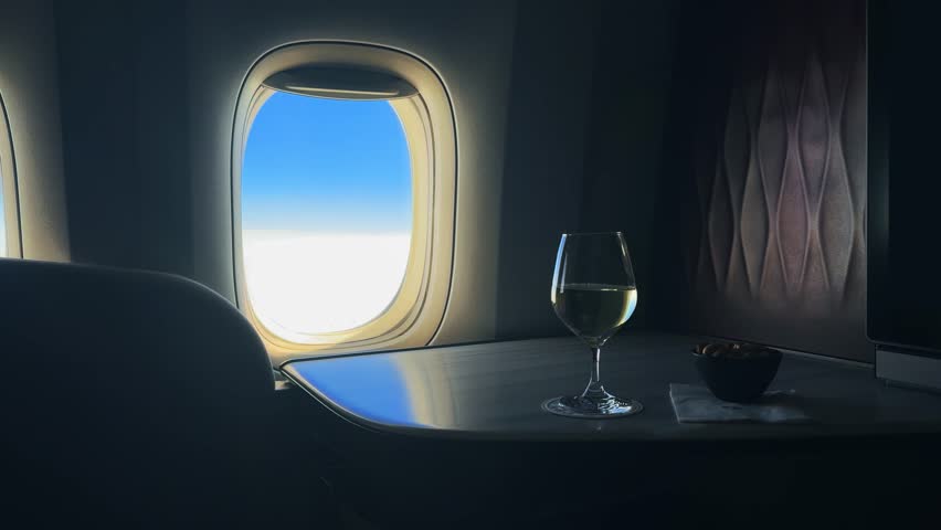 Businessman pov on flight in luxury business class airplane seat with wine glass and window view