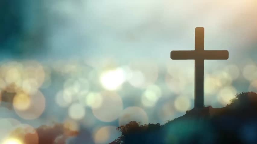 cross on a hill with a view of the city below the hill