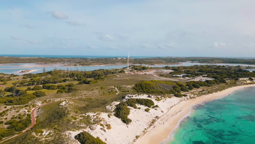 Cinematic aerial footage of Rottnest Island. A windmill sits in the middle of the island, surrounded by trees and hiking trials.