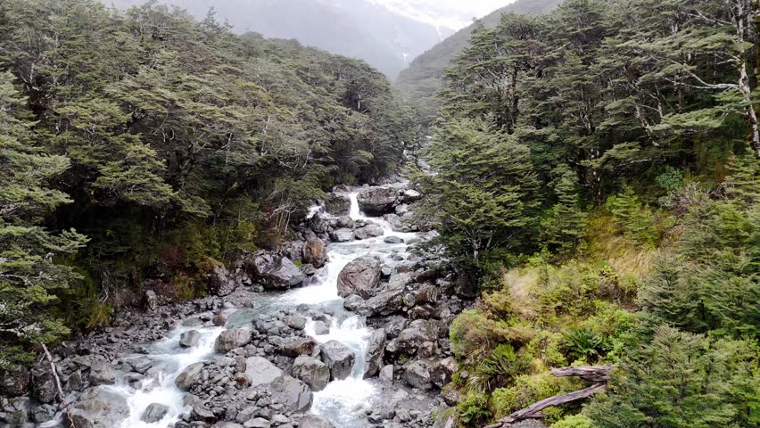 Low flying over a beautiful mountain river in the rain in New Zealand. Natural landscape. 