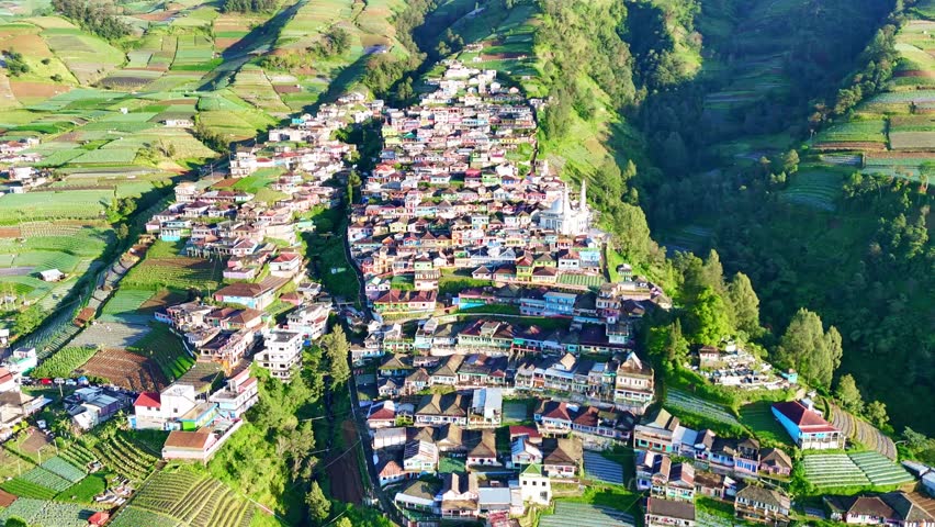 Drone shot capturing a beautiful highland community on the slope of Mount Sumbing, Central Java, with colorful houses, local architecture, and rich natural surroundings. Nepal Van Java.