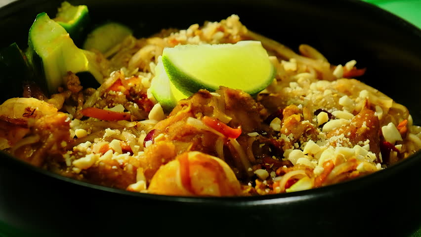Pad thai noodles with prawns near peanuts and spices. Fresh zucchini and sliced lime adds delicious notes to finished plating before serving