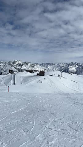 Point of view from a skier gliding down a snowy piste in a mountain resort on a sunny day