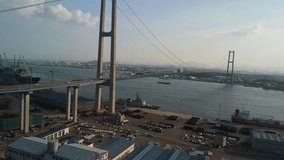 Panoramic aerial view of a grand modern suspension bridge, a bustling industrial harbor, and a shipyard. - Powered by Shutterstock - Get 15% off with code: PIKWIZARD15