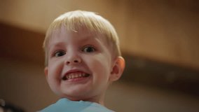Smiling young boy in light blue shirt looking directly at camera with playful expression, showing teeth with wide grin, joyful childhood moment full of innocence, captured in natural indoor - Powered by Shutterstock - Get 15% off with code: PIKWIZARD15