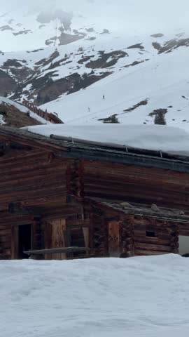 Picturesque log cabin nestled on a snowy slope with mountains in the background