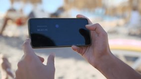 An investors hands pause over a smartphone displaying crypto or stock market assets during a beach outing. The thoughtful tapping captures a moment of financial deliberation, ideal for content about - Powered by Shutterstock - Get 15% off with code: PIKWIZARD15