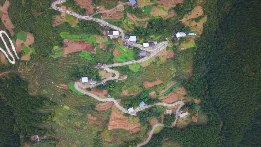 Drone top-down view of winding serpentine roads cutting through the hills of Wuxi County, Lingpaishi, China