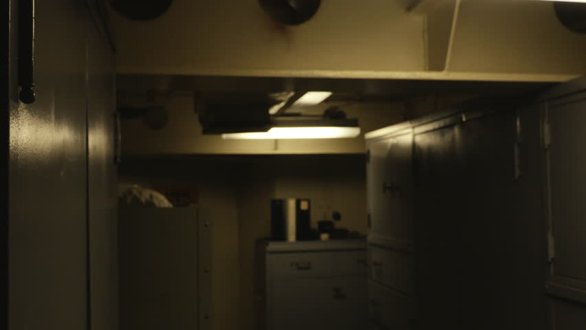 Downward moving camera revealing crew quarters inside a United States Navy ship. Interior military living space with bunks, equipment, and operational details. Useful for themes of naval operations.