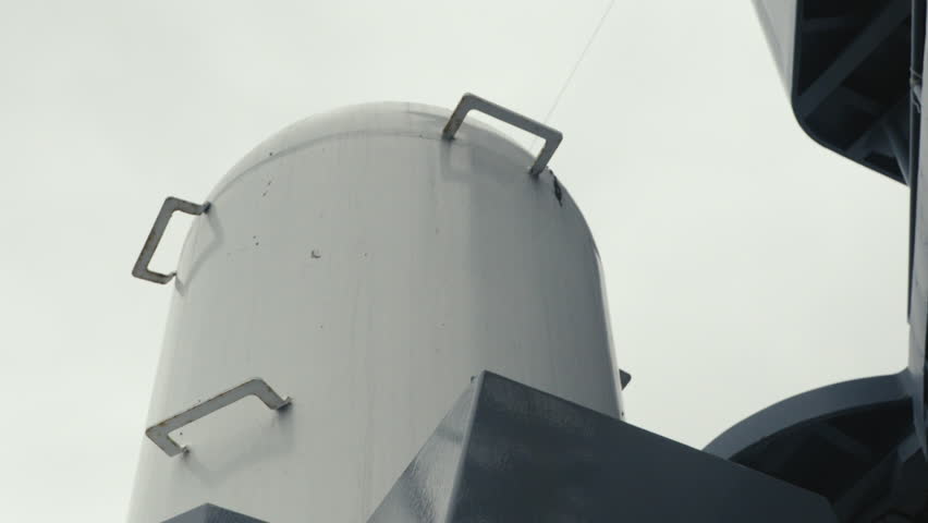 Dynamic close-up shot of a multi-barrel naval machine gun cannon mounted on a modern warship. Detailed view of the rotating turret system, military hardware, and maritime defence equipment.