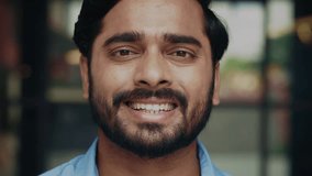 Portrait of young Indian man shows toothy smile turning head to camera on street closeup. Happy Hindu male radiates positive emotions with facial expression on urban backdrop - Powered by Shutterstock - Get 15% off with code: PIKWIZARD15