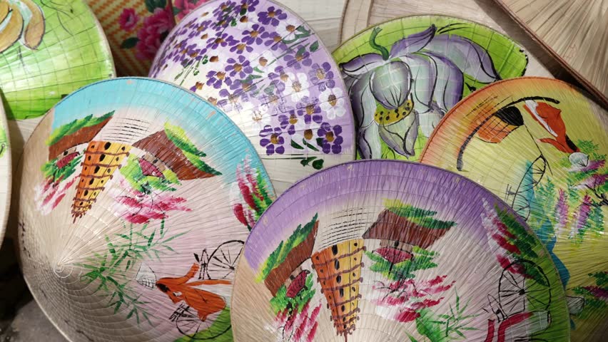 A vibrant display of traditional Vietnamese conical hats featuring hand-painted floral and landscape designs in Hue.