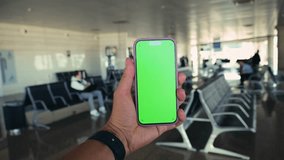 Hand holding a smartphone with a green screen in an airport terminal. Blurred travelers and modern terminal. High quality 4k footage - Powered by Shutterstock - Get 15% off with code: PIKWIZARD15