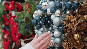 Close-up of a hand gently touching a beautifully crafted Christmas decor wreath in admiration, the festive display features elegant ornaments, pinecones, and shimmering decorations - Powered by Shutterstock - Get 15% off with code: PIKWIZARD15