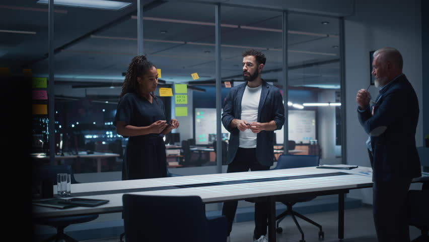Architects Collaborate Late in a Glass Office, Reviewing a Holographic Smart City Model, Futuristic Skyline Concepts, Sustainable Master Planning, and High Tech Urban Development Strategy Together.