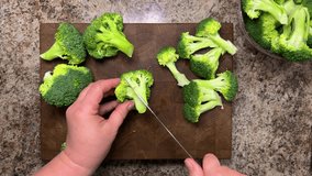 A head of broccoli is separated into florets using a knife against a wooden board. End grain cutting board made of oak. - Powered by Shutterstock - Get 15% off with code: PIKWIZARD15