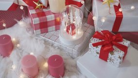 A detailed 4K view of a festive Christmas arrangement featuring red and white gifts and an illuminated snow globe with a miniature house. - Powered by Shutterstock - Get 15% off with code: PIKWIZARD15