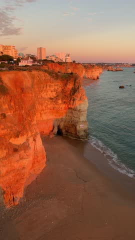 Beach Praia do Amado and city Portimao at sunset. Algarve region, southern Portugal

