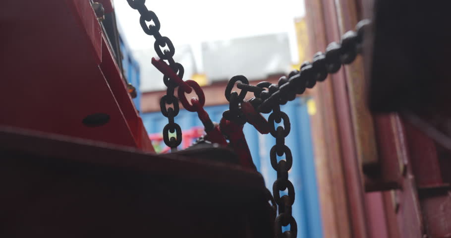 Rusty chains coil beside damp cargo containers. Metallic links glisten under cold marine light reflecting dockside endurance. Cargo ship