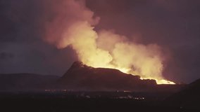 Massive night volcano eruption silhouetted against the dark sky. Bright orange lava illuminates huge billowing smoke plumes from behind the mountain. - Powered by Shutterstock - Get 15% off with code: PIKWIZARD15