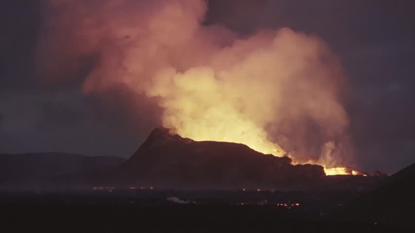Spectacular night view of volcanic eruption illuminating massive smoke cloud. Glowing lava crater casting orange light on steam and ash plume against dark sky.