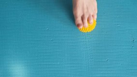 Female feet are doing foot exercises by rolling a prickly massage yellow ball under the foot on the yoga mat pressing down in different sides. Training to correct and relax the foot fascia. 4k footage - Powered by Shutterstock - Get 15% off with code: PIKWIZARD15
