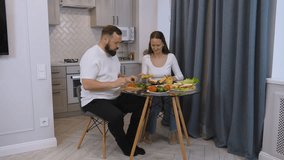 Loving couple preparing lunch in modern kitchen, woman spreading sauce on bread while partner standing nearby, sharing intimate domestic moment during meal preparation - Powered by Shutterstock - Get 15% off with code: PIKWIZARD15