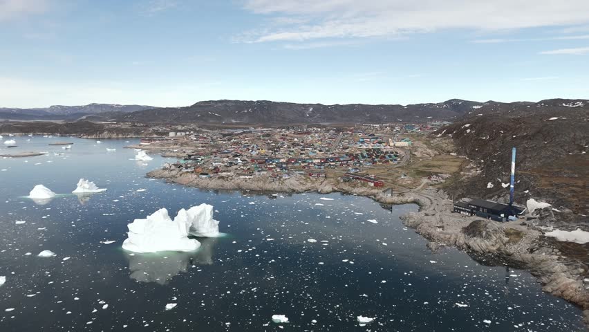 High aerial sweep over Ilulissat and massive iceberg