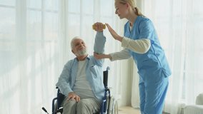 Support rehabilitation healthcare. Nurse helps old man patient in wheelchair picking up dumbbells. Paralyzed man in chair for people with disability doing sports exercise with nurse. Medical caregiver - Powered by Shutterstock - Get 15% off with code: PIKWIZARD15