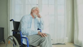 Sad senior man sitting in wheelchair looking out window in retirement home hospital. Old paralyzed man in chair for people with disability feel depressed. Lonely elderly sick man sitting on wheelchair - Powered by Shutterstock - Get 15% off with code: PIKWIZARD15