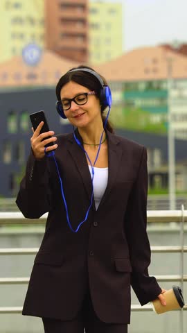 Walking along the scenic promenade, she dances gracefully, headphones on, enjoying music streamed seamlessly from an online smartphone application. Walking along the scenic promenade, she