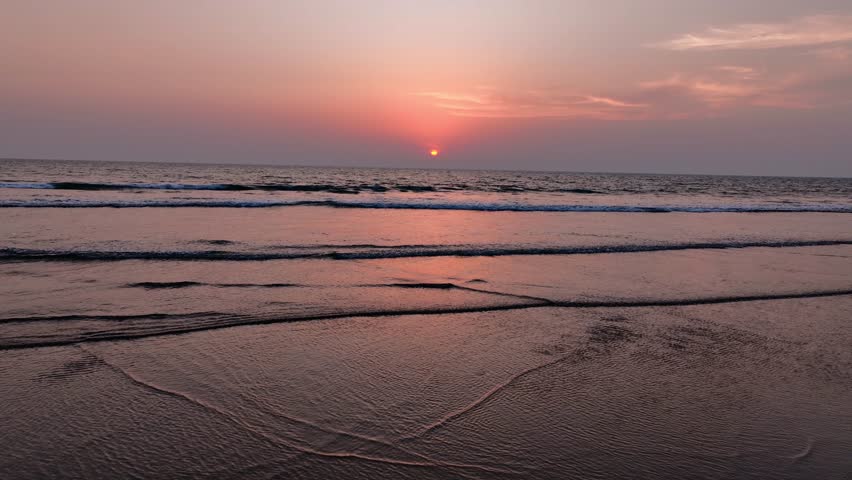 A breathtaking sunset paints the sky with vibrant hues of pink and orange over the tranquil ocean waves