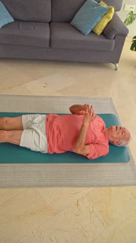 Elderly man lying on yoga mat doing leg stretches to improve flexibility and mobility at home