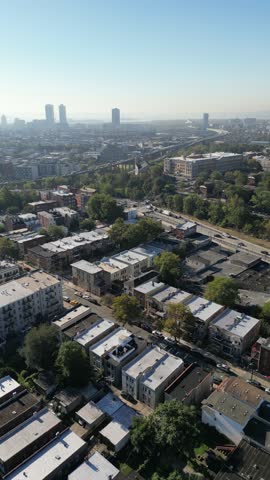 Rising drone angle over Jersey City homes highlighting compact rows, building textures, and cross streets within the urban layout.