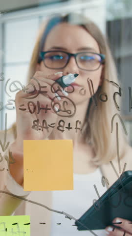 Beautiful woman developer of design office working on glass wall and calculating possible profit of new start up project ,slow motion,front view