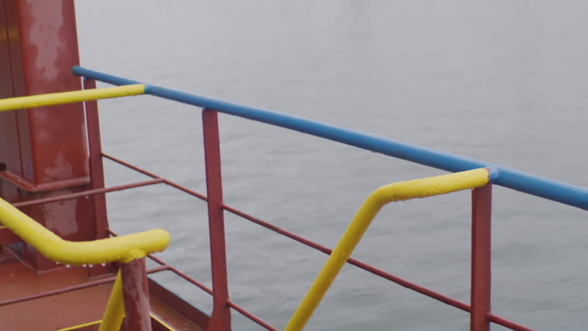Sailor in helmet carefully descends metal stairs into dim cargo hold humid marine air surrounds. Worker in helmet moves into lower deck