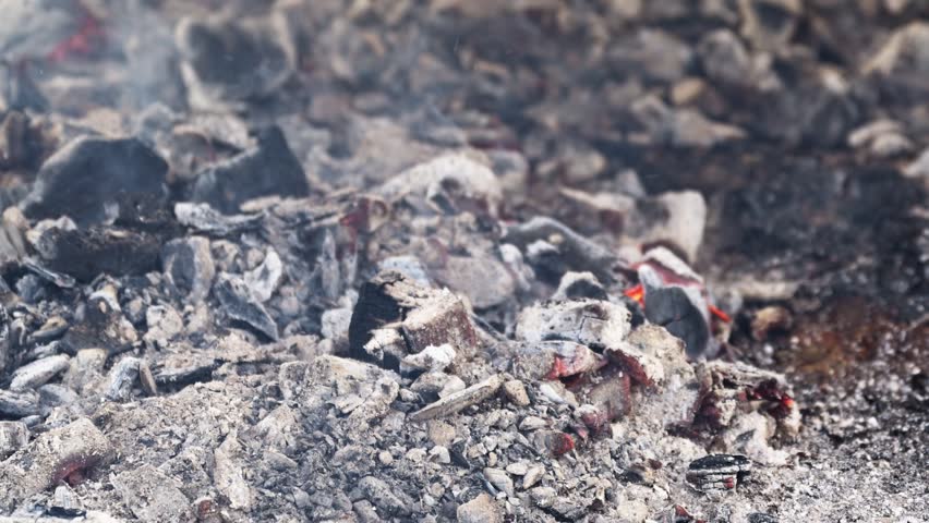 Closeup view of burning barbecue charcoal with smoke and glowing embers, heat and fire texture. 4K with selective focus.